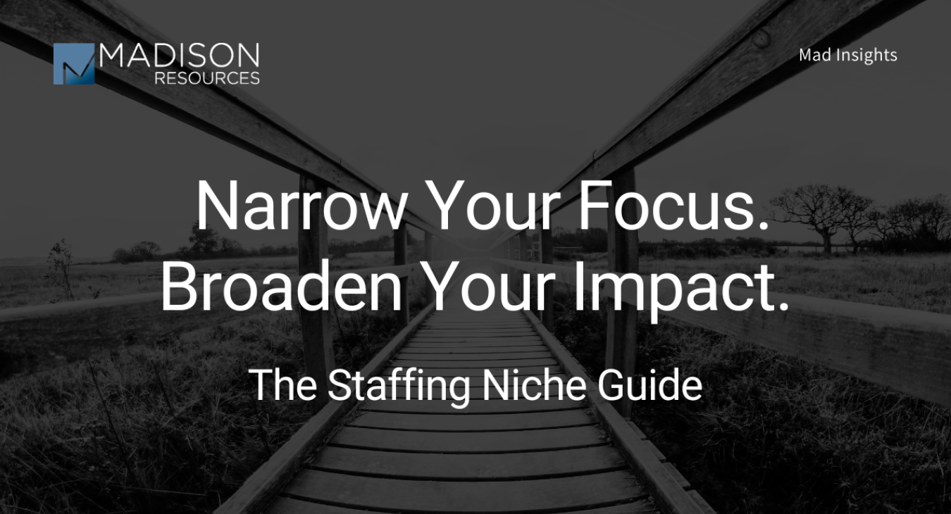 A brainstorming session with a diverse team around a conference table, with notes, charts, and a laptop displaying market research data. The focus is on identifying a niche in the staffing industry, symbolizing strategic planning and decision-making